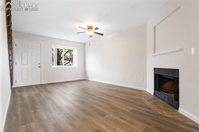 unfurnished living room with baseboards, a fireplace with flush hearth, ceiling fan, and wood finished floors