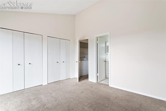 unfurnished bedroom featuring washer / dryer, multiple closets, carpet flooring, a high ceiling, and baseboards