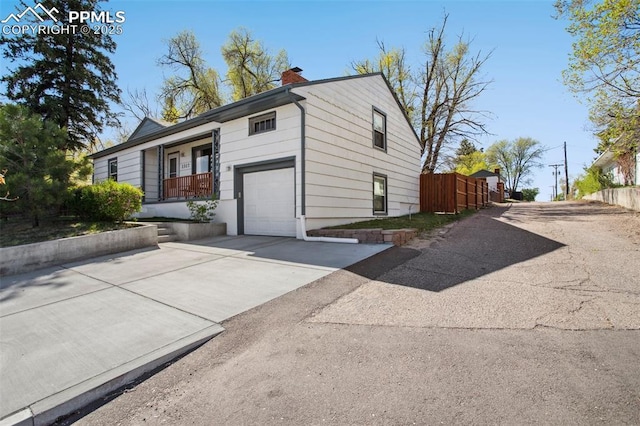 view of front of home featuring a garage, aphalt driveway, fence, a chimney, and a porch