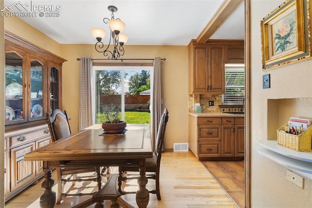 dining area with an inviting chandelier, light wood-type flooring, and visible vents