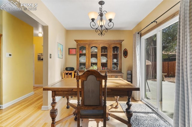 dining area with baseboards, a chandelier, and light wood-style flooring