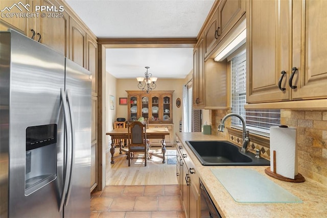kitchen with a notable chandelier, a sink, stainless steel fridge with ice dispenser, light countertops, and backsplash