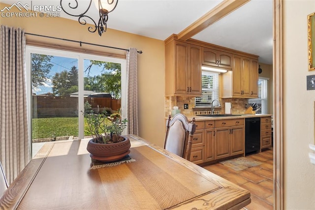 kitchen featuring plenty of natural light, a sink, black dishwasher, and light countertops