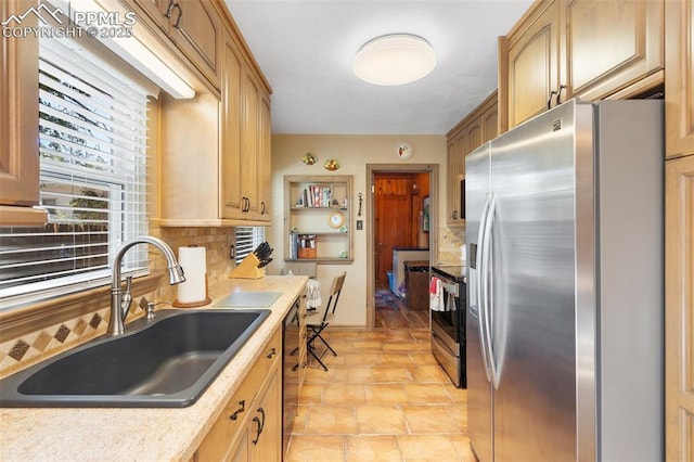 kitchen with light brown cabinetry, tasteful backsplash, a sink, light countertops, and stainless steel appliances