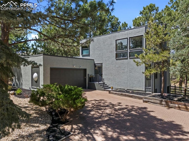 view of front of house with concrete driveway, a garage, fence, and stucco siding