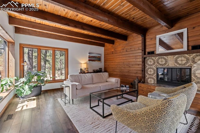 living room with a fireplace, hardwood / wood-style floors, beamed ceiling, visible vents, and wood ceiling