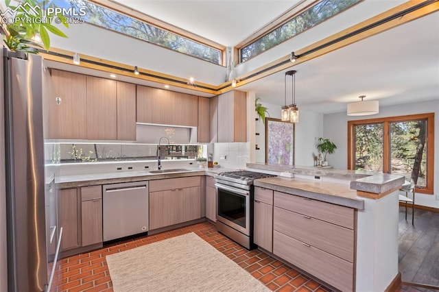 kitchen featuring a peninsula, light brown cabinets, light countertops, a sink, and stainless steel appliances