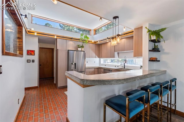 kitchen with a sink, baseboards, stainless steel appliances, and a peninsula