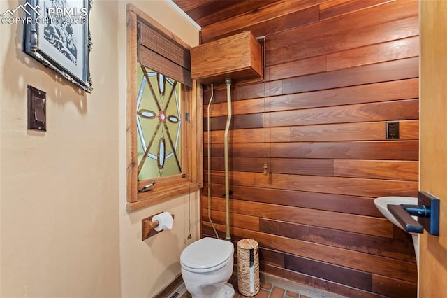 bathroom with wooden walls and toilet