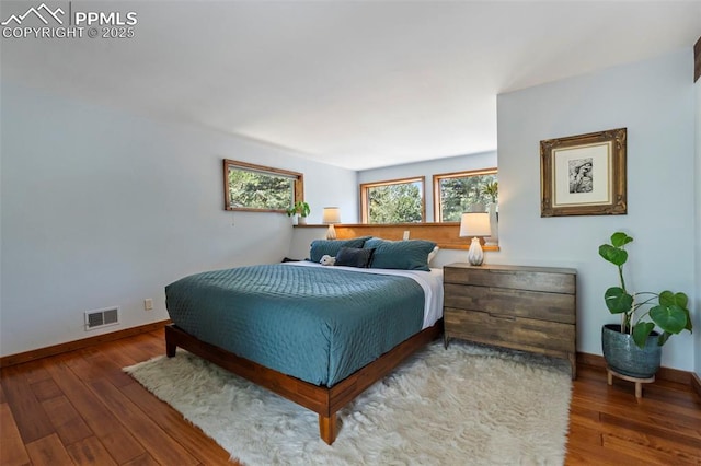 bedroom featuring baseboards, wood finished floors, and visible vents