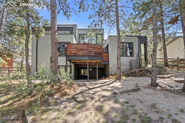back of house with a deck, fence, and stucco siding