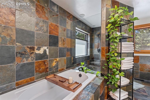 full bathroom featuring tile walls, stone finish floor, and a garden tub