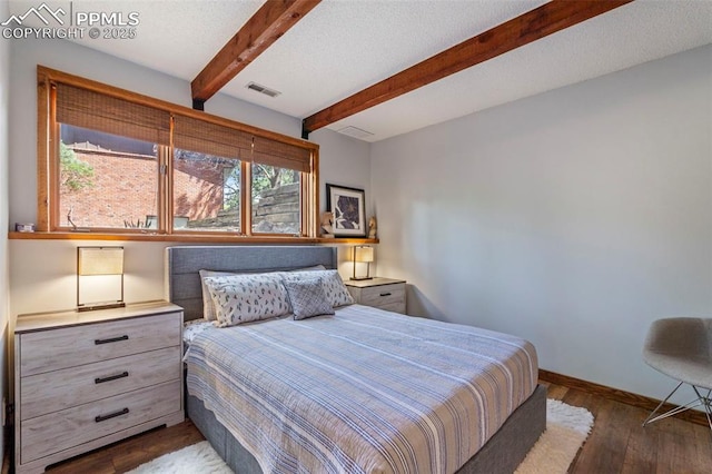 bedroom featuring dark wood-style flooring, baseboards, visible vents, and beam ceiling
