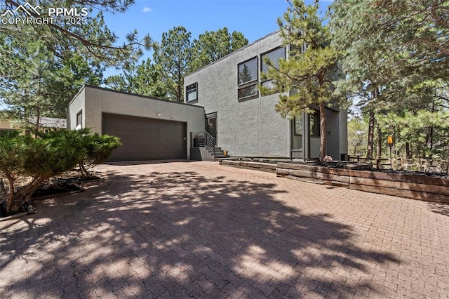 view of front facade with a garage, stucco siding, and driveway