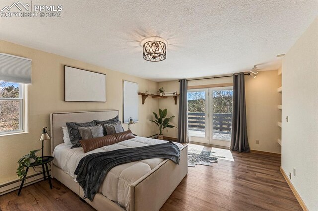 3543 Blue Mesa Dr, Divide, CO 80814 - bedroom featuring access to outside, a baseboard heating unit, wood finished floors, a textured ceiling, and baseboards