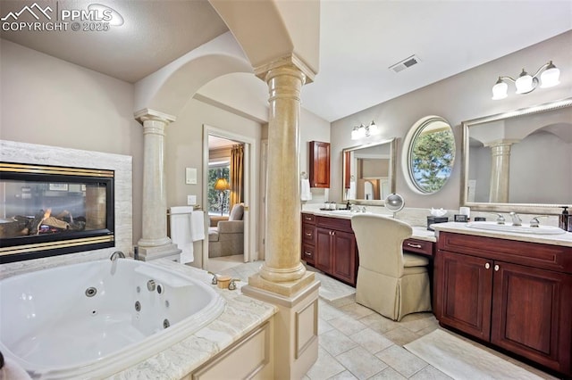 bathroom with visible vents, decorative columns, a tub with jets, and vanity