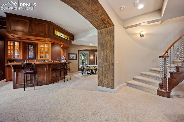 bar with wet bar, light carpet, baseboards, and stairway