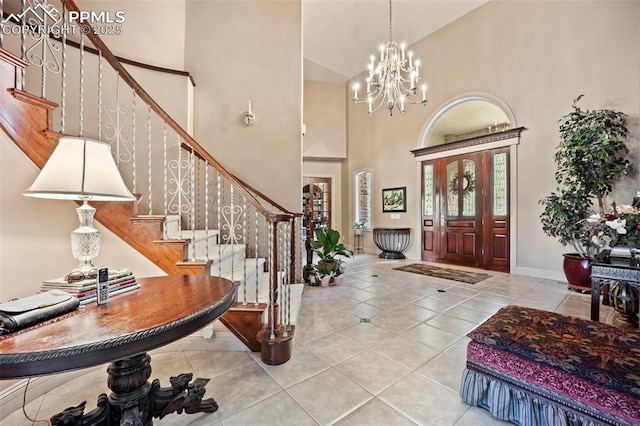 entrance foyer featuring tile patterned flooring, stairway, baseboards, a chandelier, and a high ceiling