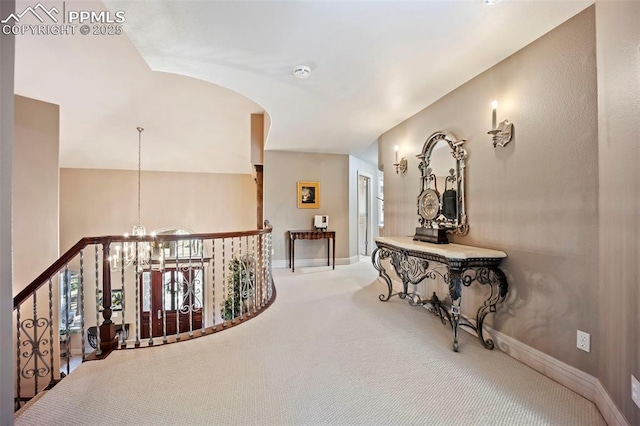 corridor with baseboards, carpet flooring, and a chandelier