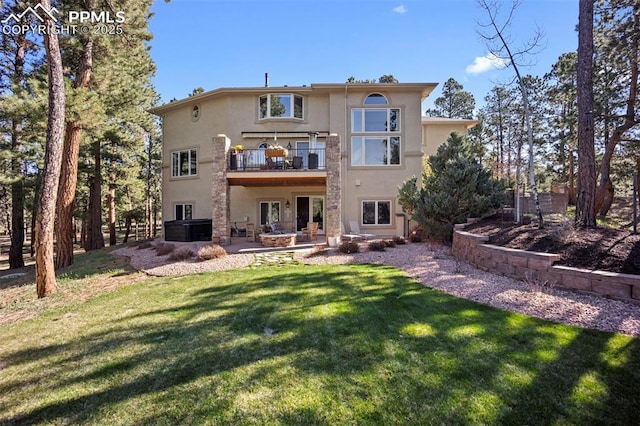 back of property featuring a lawn, a patio, a balcony, and stucco siding