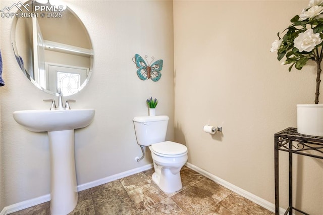 half bathroom featuring baseboards and toilet