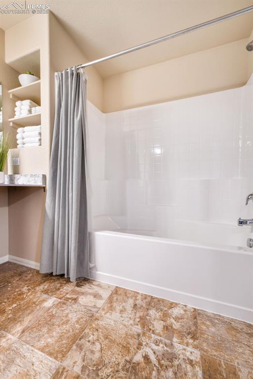 bathroom featuring baseboards and shower / tub combo