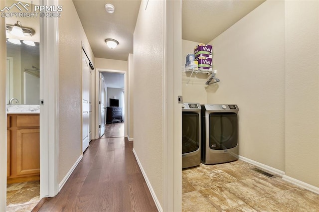 laundry area with a textured wall, laundry area, baseboards, visible vents, and washing machine and dryer