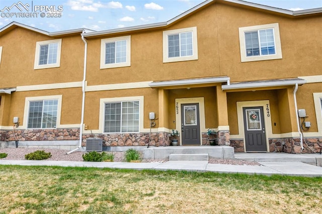 multi unit property featuring central AC, a front lawn, stucco siding, and stone siding