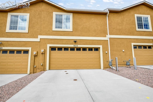 view of front of property with stucco siding, an attached garage, and driveway