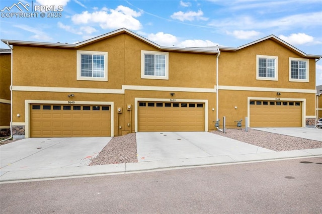 view of front of home with a garage, stucco siding, and concrete driveway