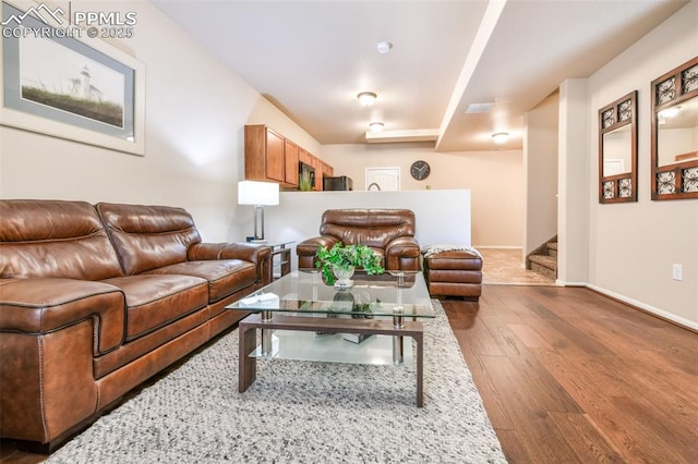 living area with baseboards, stairs, and wood finished floors