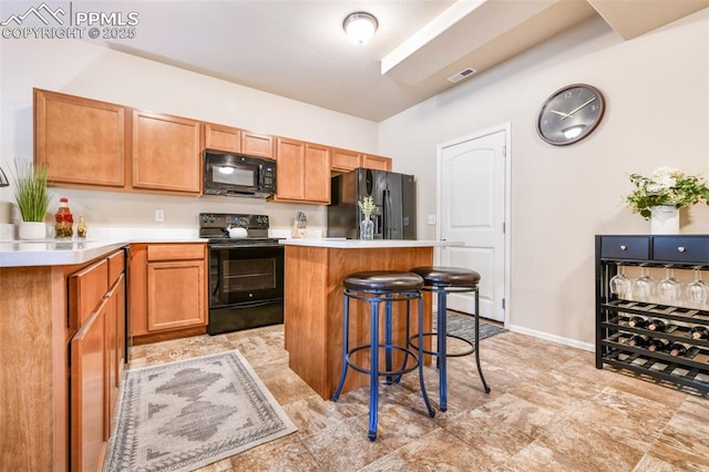 kitchen featuring a kitchen island, a kitchen bar, visible vents, light countertops, and black appliances