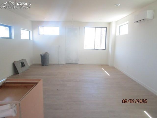 1019 Race St, Colorado Springs, CO 80904 - below grade area with light wood-style floors, baseboards, and an AC wall unit