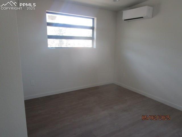 1019 Race St, Colorado Springs, CO 80904 - empty room featuring an AC wall unit, baseboards, and wood finished floors