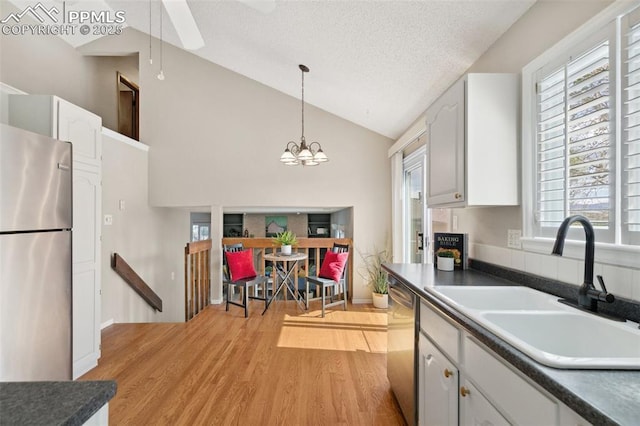 kitchen featuring a textured ceiling, appliances with stainless steel finishes, dark countertops, light wood-type flooring, and a sink