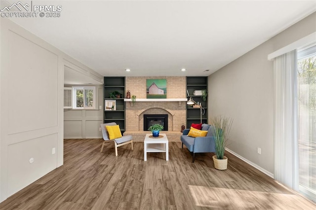 living area featuring baseboards, a wealth of natural light, wood finished floors, and a fireplace