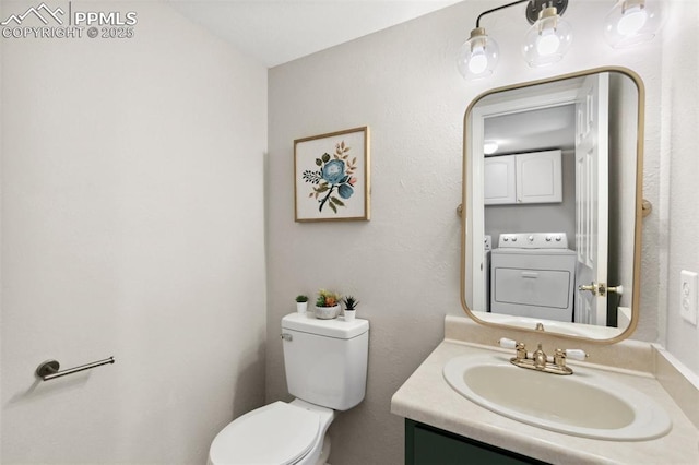 half bath featuring toilet, washing machine and dryer, and vanity