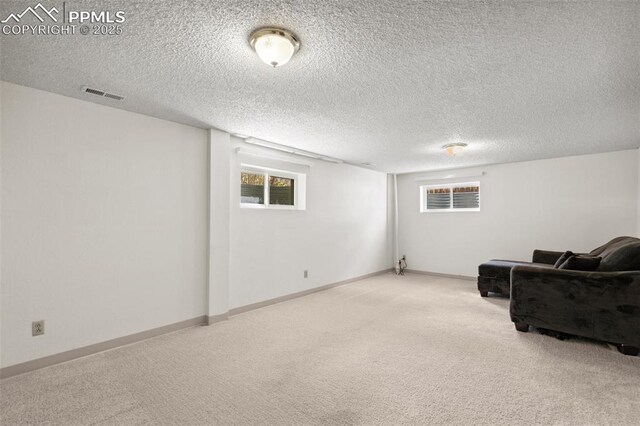 below grade area featuring carpet floors, a textured ceiling, visible vents, and baseboards