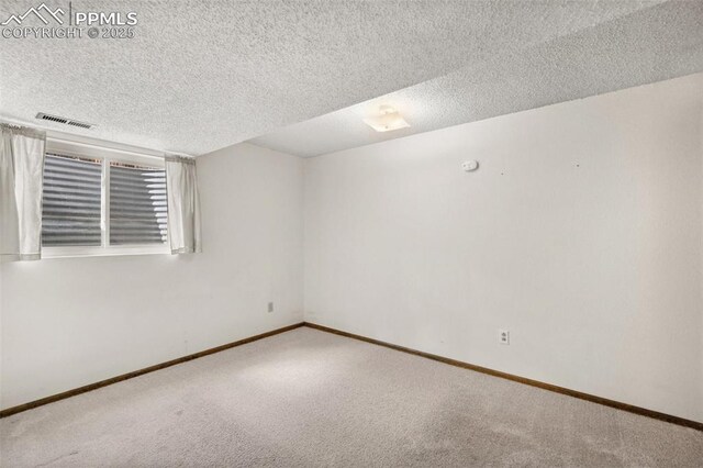 empty room with baseboards, carpet, a textured ceiling, and visible vents