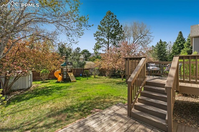 view of yard featuring a fenced backyard, an outdoor structure, a deck, and a storage shed