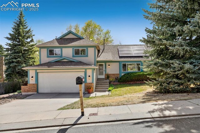 view of front of home featuring roof mounted solar panels, a shingled roof, concrete driveway, and brick siding