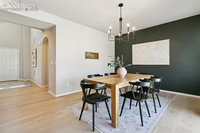 10323 Elevated Ln, Colorado Springs, CO 80924 - dining area with arched walkways, baseboards, an inviting chandelier, and light wood-style flooring