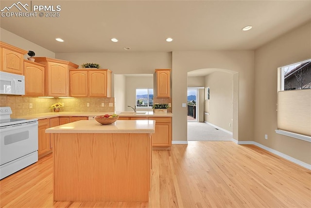 kitchen with light countertops, light brown cabinetry, and white appliances
