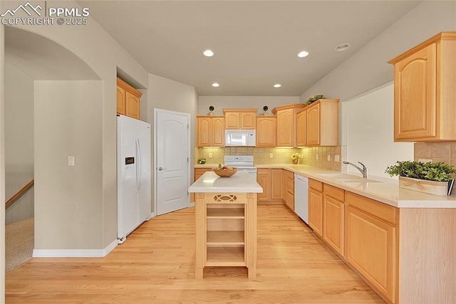 kitchen featuring a sink, light wood finished floors, light brown cabinetry, and white appliances