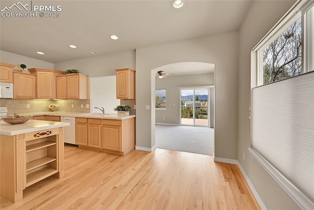 kitchen with light countertops, arched walkways, light brown cabinets, and white appliances