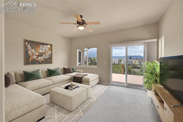 living area with a ceiling fan, baseboards, and light carpet