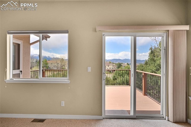 doorway to outside with carpet floors, baseboards, a mountain view, and plenty of natural light