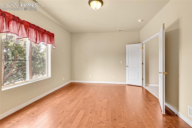 unfurnished room with baseboards and light wood-style flooring