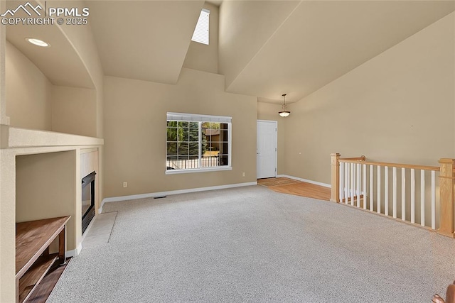 unfurnished living room featuring high vaulted ceiling, baseboards, carpet, and a tile fireplace