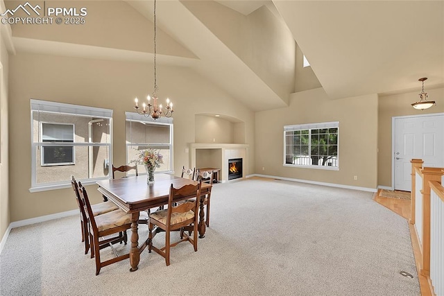 dining room featuring a glass covered fireplace, high vaulted ceiling, baseboards, and light colored carpet